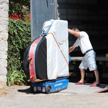 L'arrivée du piano. Bruno Prevalet pilote le petit robot transporteur